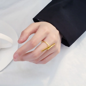 Anello aperto geometrico a T dorato minimalista indossato con una giacca nera da abito