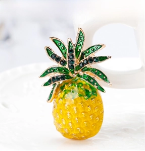 Macro shot of pineapple brooch with yellow enamel texture and green rhinestone details