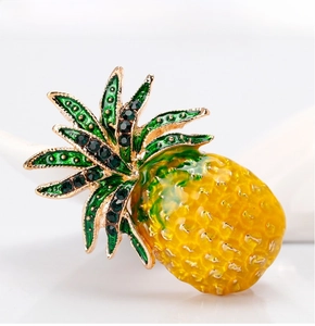 Macro shot of pineapple brooch with yellow enamel texture and green rhinestone leaves