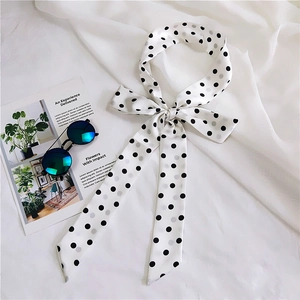 Detailed view of polka dot long skinny silk scarf tied in bow on white fabric