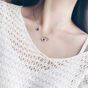 Elegant rose gold evil eye necklace with blue crystals on woman's neck, double layer design