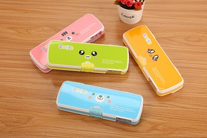 Detail of four colorful cartoon plastic pencil cases with built-in sharpener on a wood table