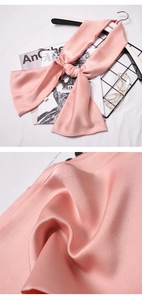 Close-up detail showing the glossy pink silk texture and sheen of the narrow scarf