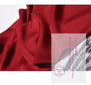 Detailed view of dark red satin fabric with soft folds and elegant glossy texture