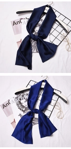 Detail of navy and royal blue silk scarves tied neatly on a white fabric background
