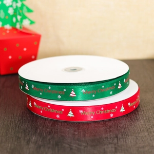 Red and green Christmas satin ribbons with Merry Christmas print on wooden table