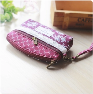 Detail of purple floral coin purse with double zippers, lace trim, and wrist strap