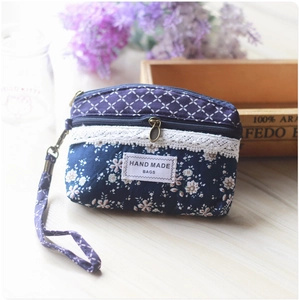Detail view of a floral blue fabric coin purse with lace trim and hand made bags label