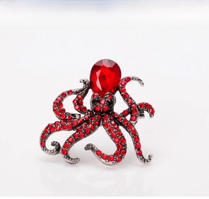 Detailed close-up of octopus brooch with red crystal pave and pear-cut ruby center stone