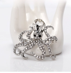 Detailed view of silver octopus brooch with sparkling rhinestones on a hand model