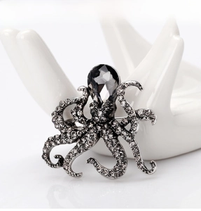 Detailed view of octopus brooch with dark grey crystals on white ceramic stand