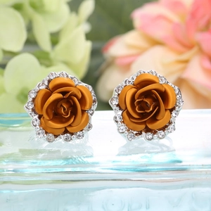 Macro shot of orange rose stud earrings with white zircon crystals and silver metal base