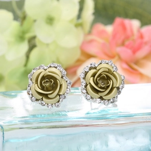 Macro shot of rose flower stud earrings with green petals and sparkling white rhinestones