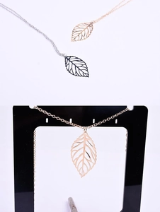 Detailed view of hollow leaf necklaces in gold, black, and silver finishes on a display