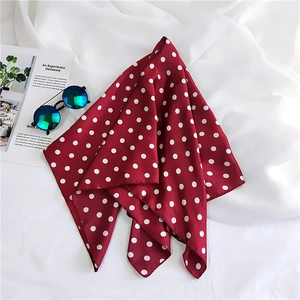 Close-up of red silk scarf with white polka dots styled with sunglasses and magazine
