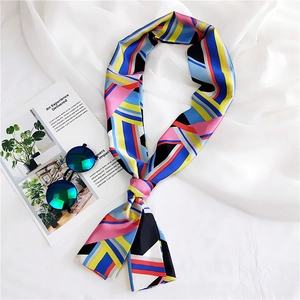 Detail of a vibrant geometric silk scarf styled with sunglasses on a white fabric backdrop