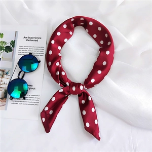 Detail view of a bright red polka dot silk scarf with smooth satin texture and elegant knot