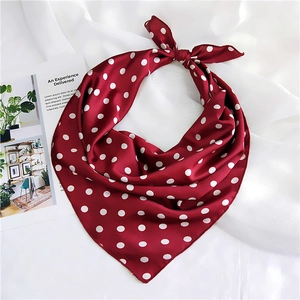 Detailed view of red polka dot silk scarf with elegant satin sheen on soft white fabric