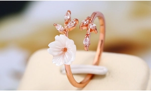 Macro shot of rose gold open ring featuring a white shell flower and zircon leaves