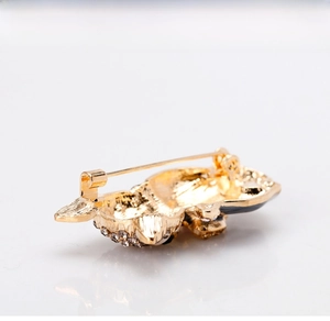 Detail of gold-plated alloy brooch featuring white rhinestones and a secure metal clasp back