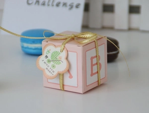 Pink paper gift box with gold ribbon and baby themed decorative tag for candy packaging
