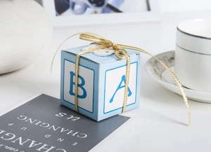 Detail of blue candy box with golden ribbon and alphabet letters for party favors