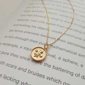 Detailed macro of 925 sterling silver gold Fleur-de-lis coin pendant on vintage book