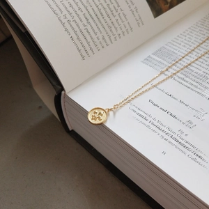 Detailed shot of vintage gold fleur-de-lis pendant necklace on an open art book