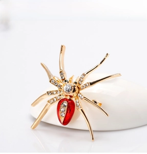 Macro view of gold spider brooch featuring red teardrop stone and crystal pavé legs