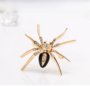 Detailed macro shot of a spider brooch with black enamel, crystals, and green gem eyes