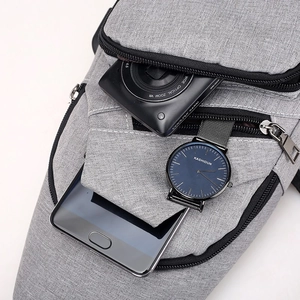 Grey nylon sling bag with multiple zip pockets for gadgets like cameras and phones