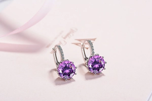 Macro shot of silver hoop earrings featuring deep magenta round-cut zircon stones