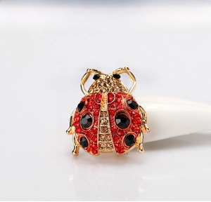 Detailed close-up of a ladybug brooch featuring red rhinestones and black gemstones