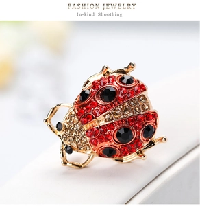 Macro detail of ladybug brooch featuring red rhinestones and black crystal spots