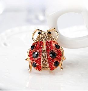 Macro detail of ladybug brooch featuring red and champagne rhinestones on gold base