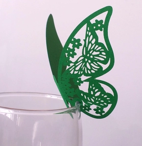 Detail of green laser-cut butterfly paper card attached to a glass rim for wedding decor