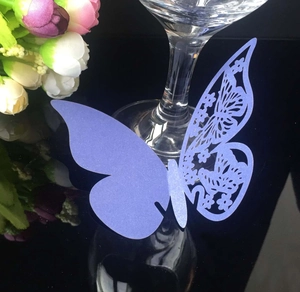 Macro detail of purple laser-cut butterfly place card on a crystal wine glass rim