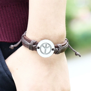 Adjustable brown leather bracelet with silver peace sign charm worn on a wrist