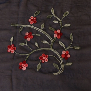 Detailed close-up of handmade floral embroidery with red and pink yarn flowers on scarf