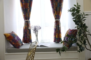 Detail of bohemian style patchwork curtains and matching cushions with elegant tassels