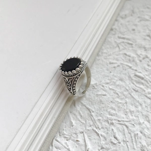 Macro shot of vintage S925 silver ring featuring an oval black agate with floral engraving