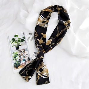 Detailed close-up of a long silk scarf with vintage gold chain and buckle patterns