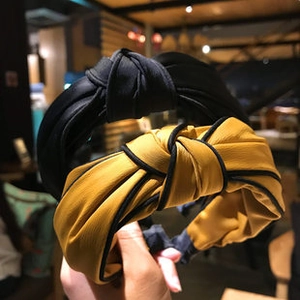 Detailed close-up of wide knotted headbands in mustard yellow and black textured fabric