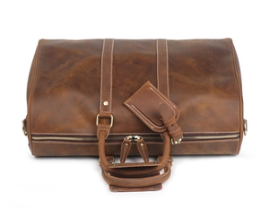 Detail of vintage brown crazy horse leather duffel bag with stitching and luggage tag