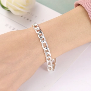 Bracelet chaîne Figaro en argent poli porté au poignet avec une rose blanche en fond
