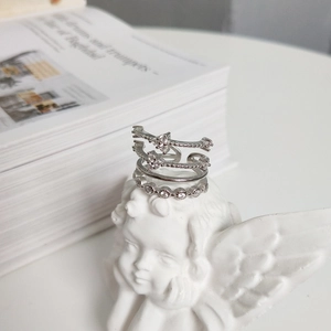 Detail of three-piece silver 925 stackable rings with white zircon on an angel statue