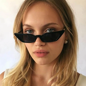 Vintage black cat eye sunglasses with slim plastic frame worn by model on beige background