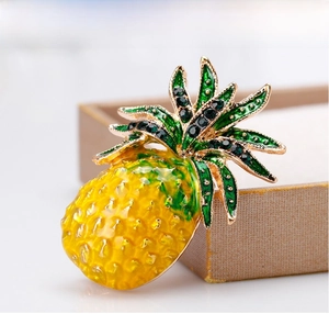 Detail of pineapple brooch with green rhinestones and gold enamel on jewelry box