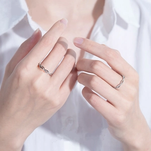 Silver plum blossom intertwining couple rings worn by hand on a white shirt background