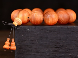 Macro detail of natural wooden prayer beads with a unique gourd pendant on dark wood